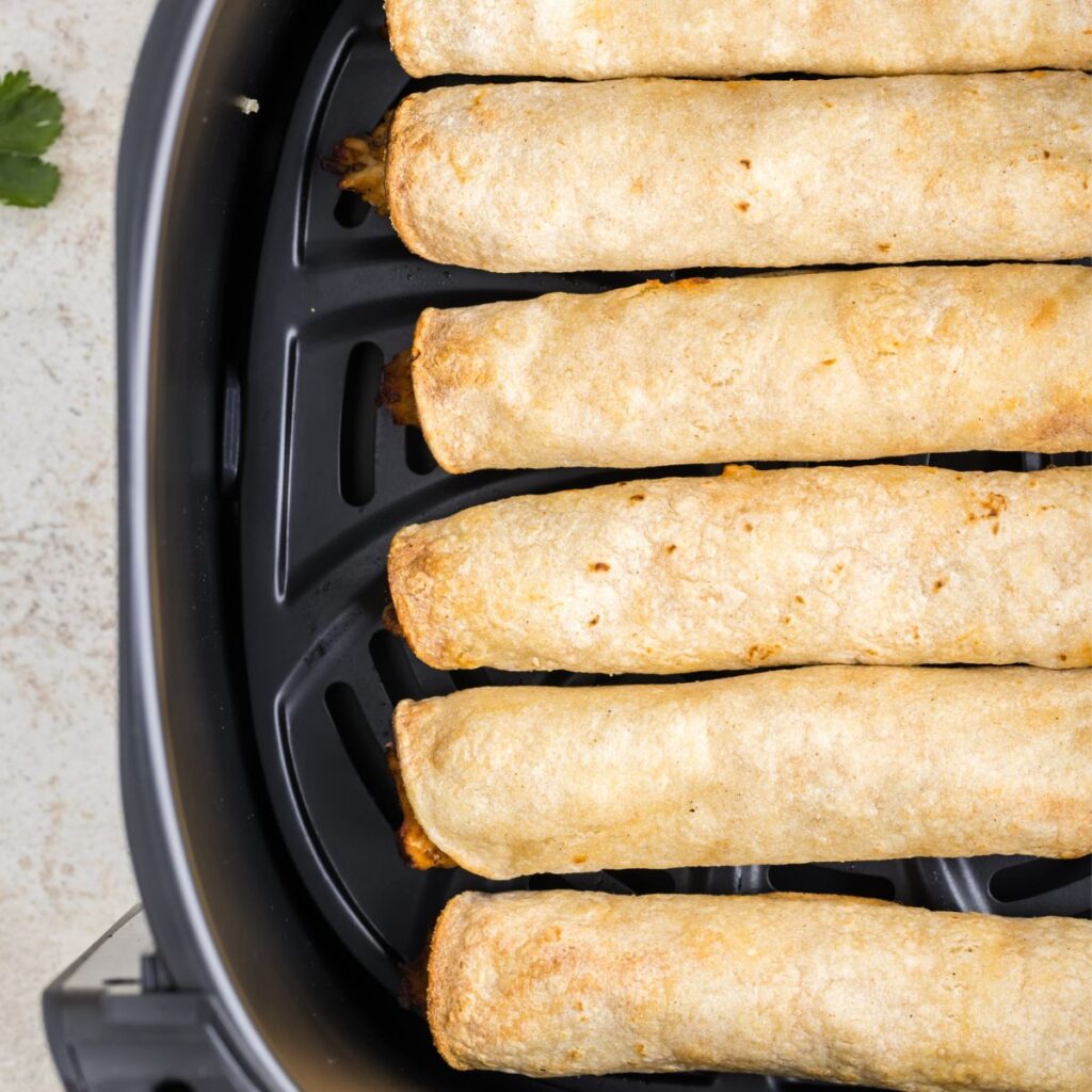 overhead photo of taquitos inside the air fryer basket. 