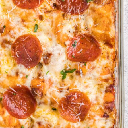 A casserole dish with pepperoni on top and cheese.