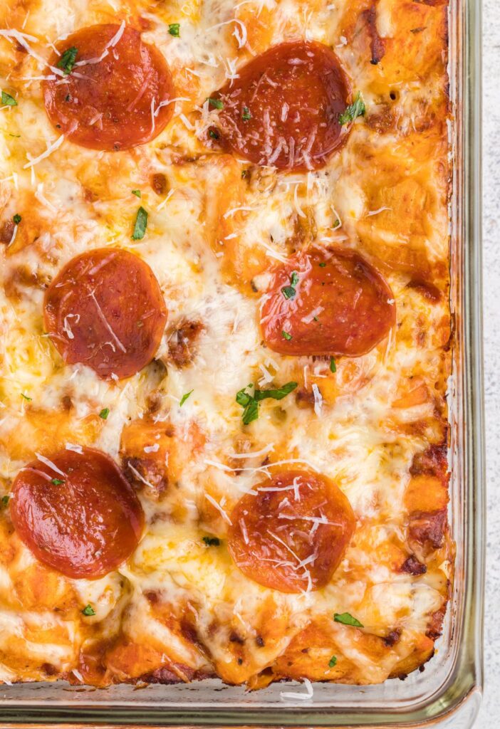 A casserole dish with pepperoni on top and cheese. 
