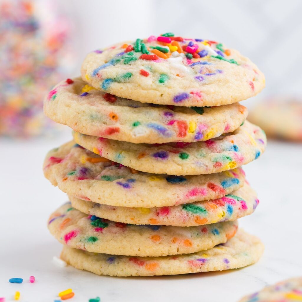 Stack of cookies with colored sprinkles around it. 