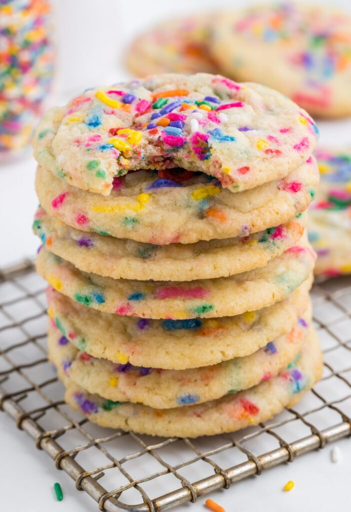 stack of sprinkle cookies with the top having a bite taken out of it. 