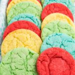 A blue tray with a cloth in it holding rows of colored cookies.
