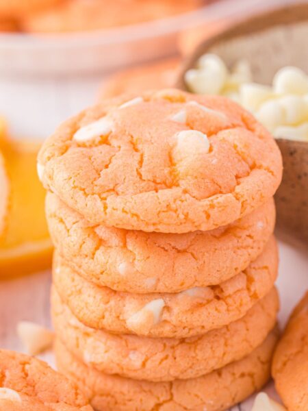 Stack of orange cookies with white chips.