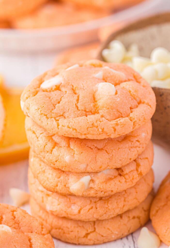 Stack of orange cookies with white chips. 