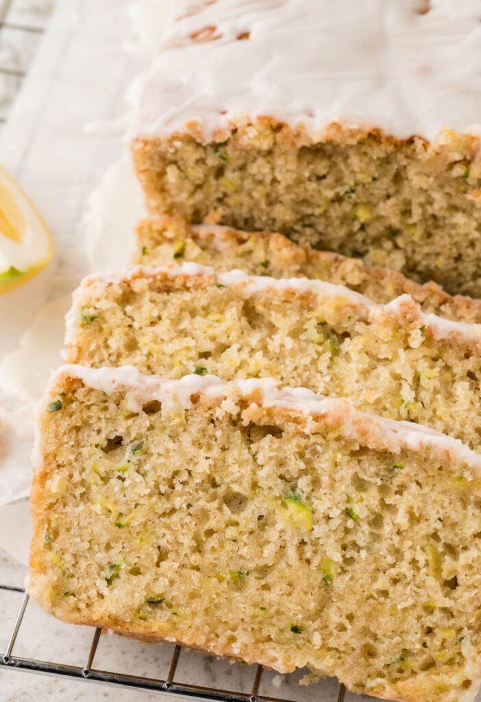 A sliced loaf of lemon zucchini bread on a cooling rack. 