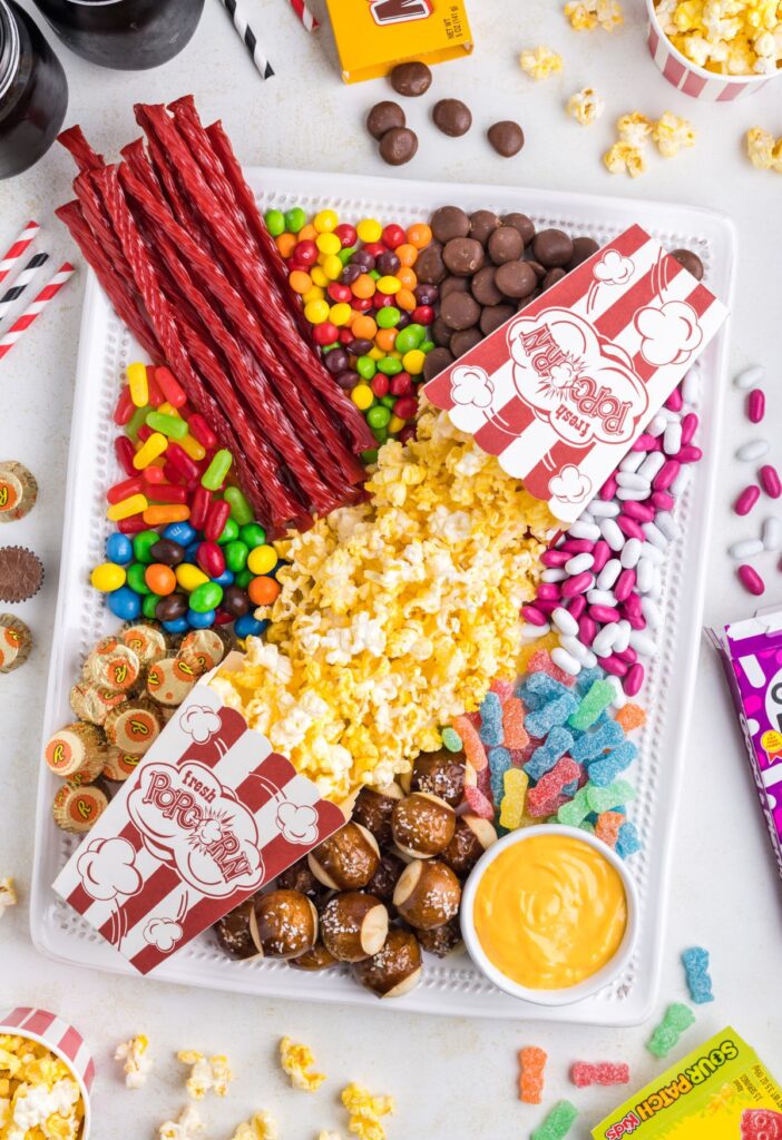 A snack board with some candy around the tray. 