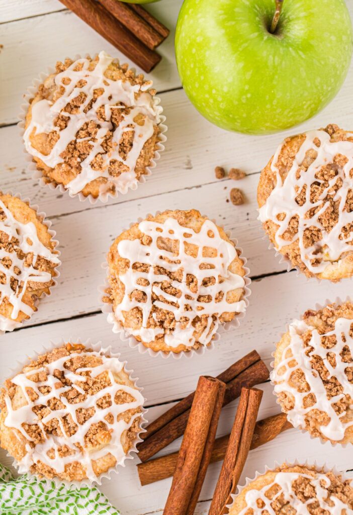 Overhead picture of muffins with cinnamon sticks and green apples. 