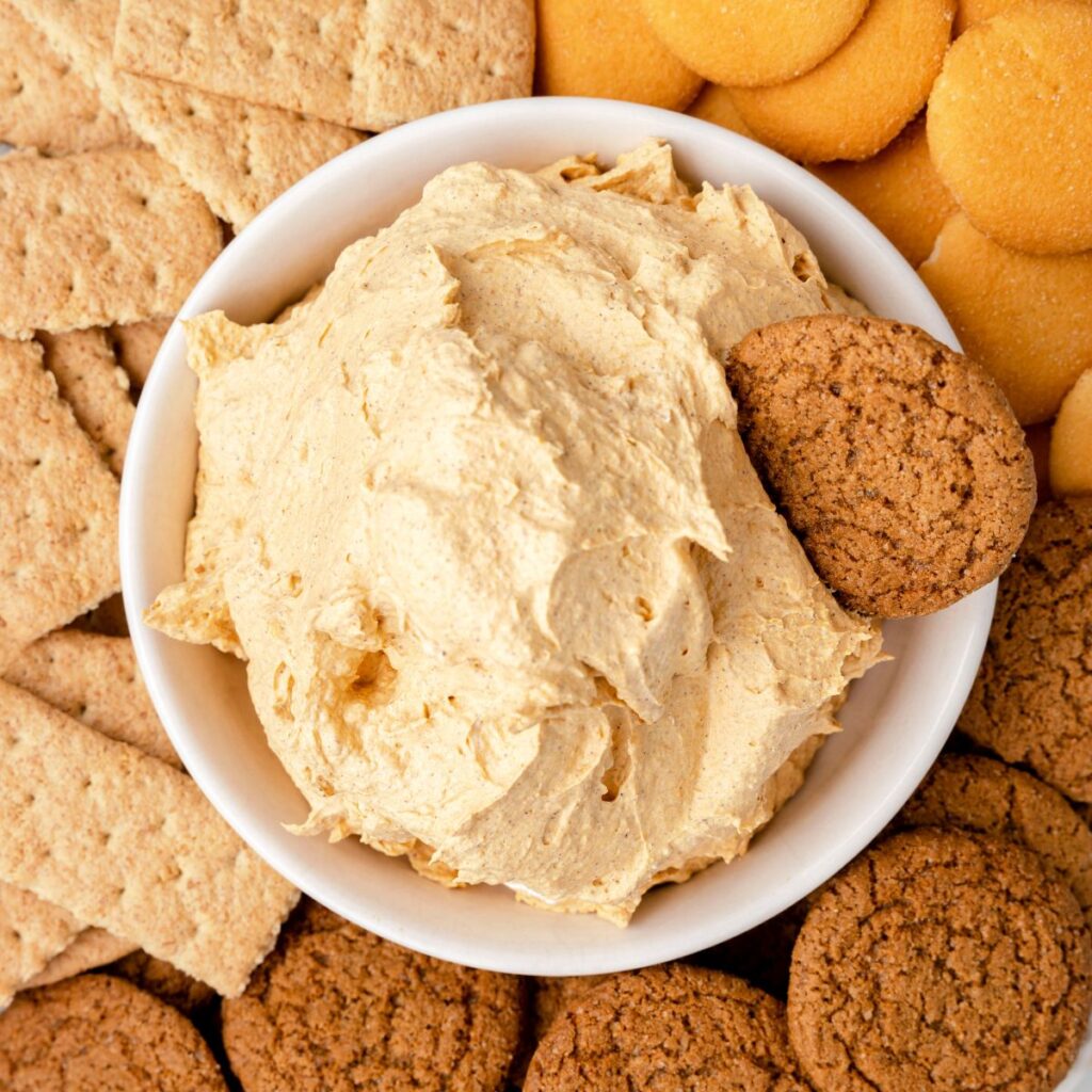 A bowl of dip with cookies around it. 