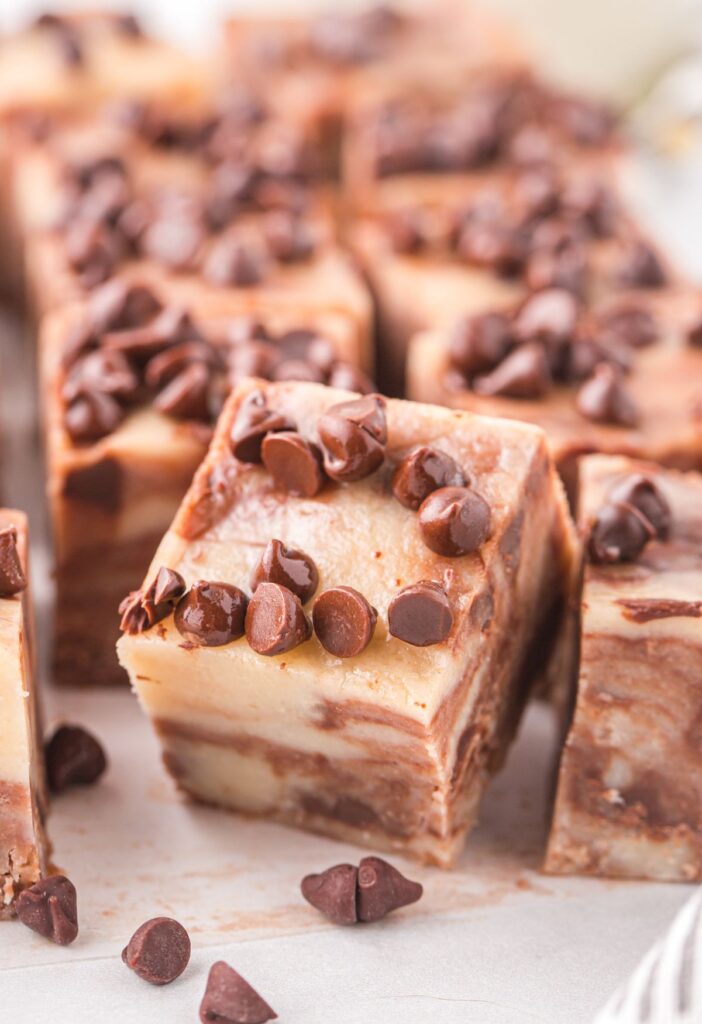 A piece of fudge propped up against another one with chocolate chips. 