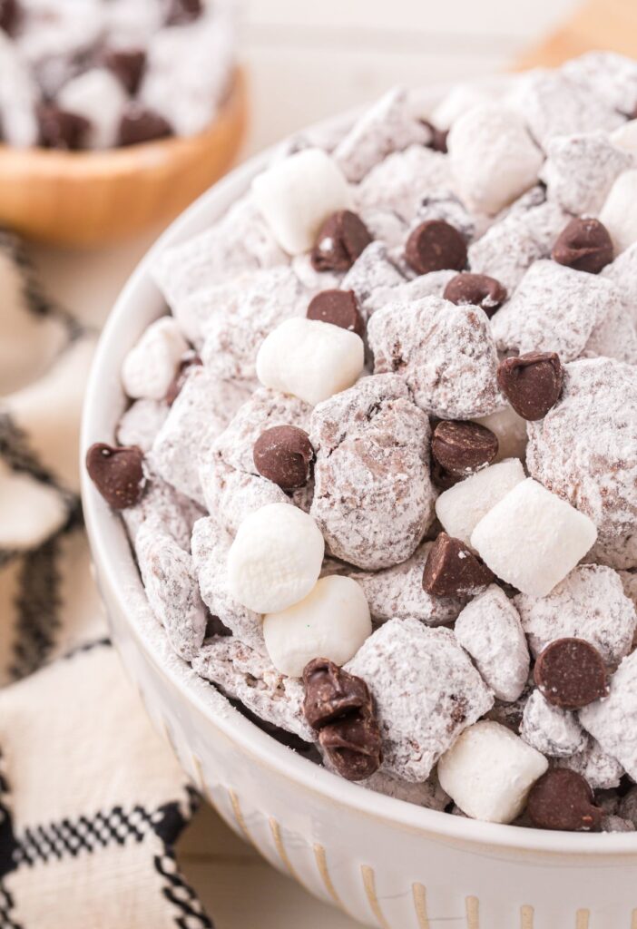 Side view of a bowl of hot chocolate muddy buddy puppy chow mix.